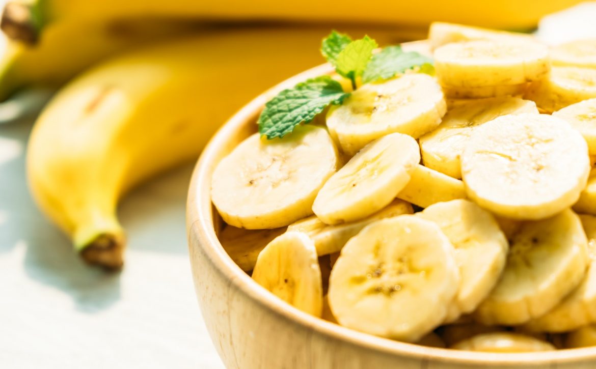 Raw yellow banana slices in wooden bowl